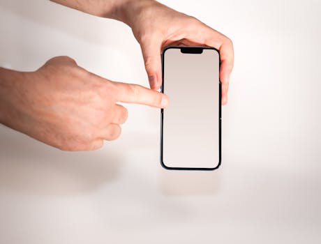 Hand pointing at blank smartphone screen, ideal for app mockups and technology concepts.