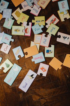 A collection of educational puzzle pieces with words and illustrations on a wooden parquet floor.