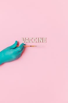 A gloved hand holds a syringe next to 'VACCINE' text on a pink background.