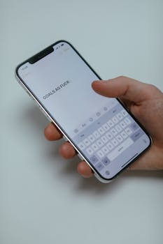 Close-up of a hand holding a smartphone displaying a motivational message, emphasizing goals.