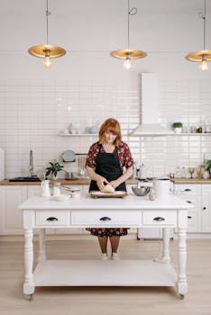 Woman baking and kneading dough in a bright, stylish kitchen with elegant details.